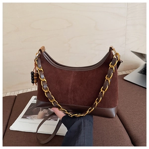 Detail of caramel suede crescent bag with gold chunky chain strap and beaded charm