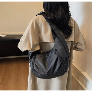 Detail of black nylon crescent crossbody bag featuring multiple functional zipper pockets