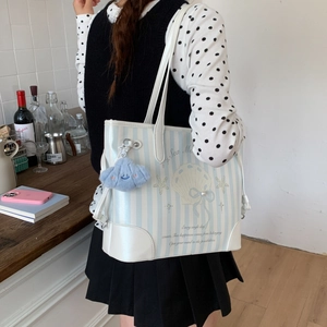 Détail du sac cabas à rayures bleues et blanches avec nœud perlé et nuage en peluche