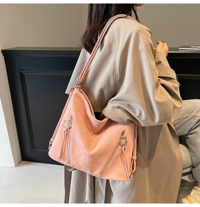 Detail of pink faux suede tote featuring star-shaped zipper pulls and adjustable strap