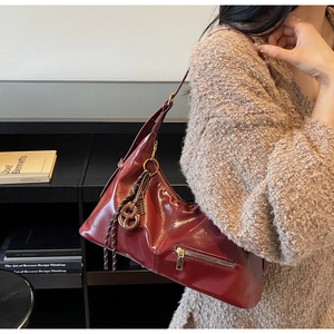 Détail du sac hobo vintage bordeaux avec fini brillant et pendentif tressé déco