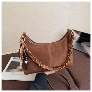 Detail of vintage brown suede crescent bag with gold chain and beaded ornament