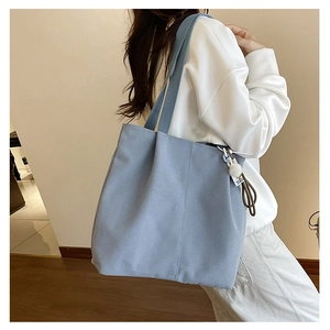 Detail view of light blue canvas tote bag with side stitching and soft pompom charm