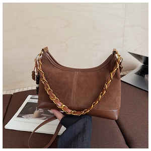 Close-up of brown suede hobo bag featuring gold chain and retro beaded charm detail