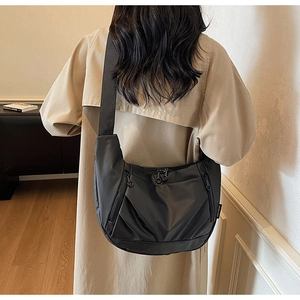 Detail of black nylon crescent bag featuring metal zippers and wide fabric shoulder strap
