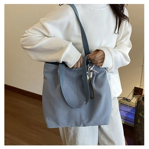Close-up of a light blue canvas tote bag with dual handles and long shoulder strap