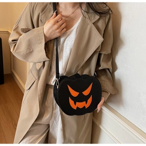 Detail of a pumpkin-shaped Halloween crossbody bag with orange accents on a leather strap