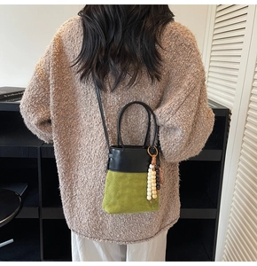 Detail of avocado green suede bucket bag with diamond quilting and beaded tassel
