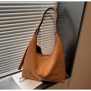 Detailed close-up of brown suede hobo bag with vertical stitching and adjustable leather strap