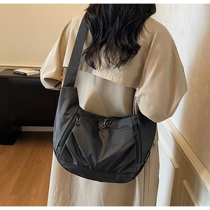 Detail of black crescent crossbody bag with dual vertical zipper pockets and wide strap
