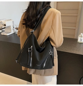 Detail of black large-capacity tote bag with star zippers and brand logo on model