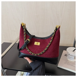 Close-up of quilted burgundy suede bag with gold chain strap and metallic twist lock