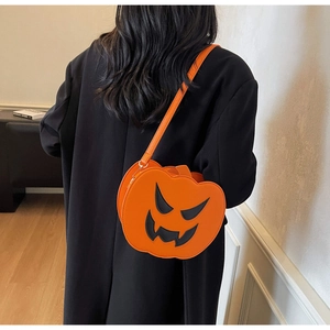 Detail of a bright orange pumpkin crossbody bag with evil smile design on black coat