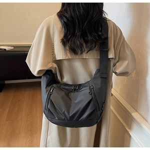 Close-up of black nylon crescent bag with double front zippers and wide shoulder strap