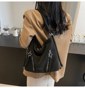 Detail of black large capacity tote bag with silver star pendants on zippers