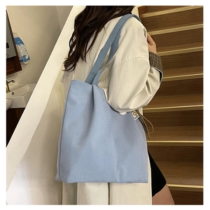 Detailed view of light blue canvas tote bag showing wide shoulder strap and side label
