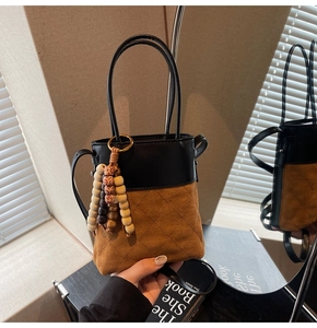Detail of contrast bucket bag with quilted leather base and beaded tassel charm