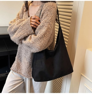 Suede-textured black large hobo bag worn by model over a brown knit sweater