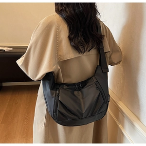 Detail of black nylon crescent bag showing side zippers and wide webbing shoulder strap