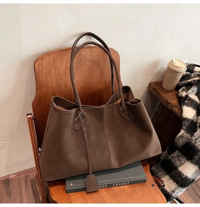 Close-up of brown matte tote bag on wooden chair showing soft texture and large capacity