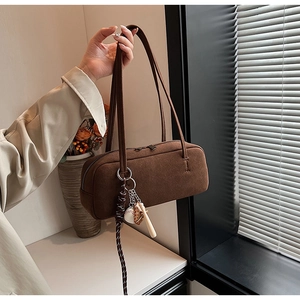 Braune Wildleder-Schultertasche mit Baseball-Anhänger am Modell für den täglichen Weg