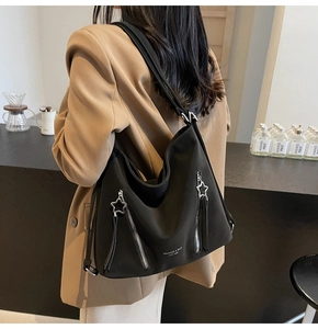 Detail of a black matte tote bag featuring star zippers and Mikaxiqi logo on a model
