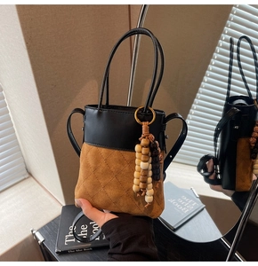 Detail of vintage suede bucket bag with leather patchwork and wooden bead tassel decor