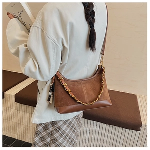 Détail du sac à bandoulière en daim et cuir avec chaîne en métal et perles en bois