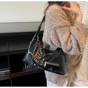 Gros plan du sac hobo en cuir brillant noir avec fermetures éclair et breloques