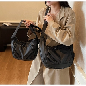 Close-up of black Oxford cloth hobo bag with multiple zipper pockets and wide woven strap