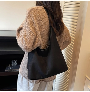 Detail of black suede hobo bag with vertical stitching shown on model's shoulder