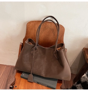 Detail of coffee brown matte faux suede tote bag with vertical stitching on wooden chair