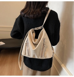 Detail view of cream tote bag with silver side zippers and star pendant on a model