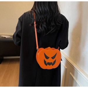 Detail of the orange pumpkin crossbody bag with a black jack-o'-lantern face and thin strap