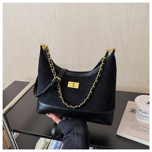 Detail of black quilted hobo bag with gold chain strap and suede leather texture