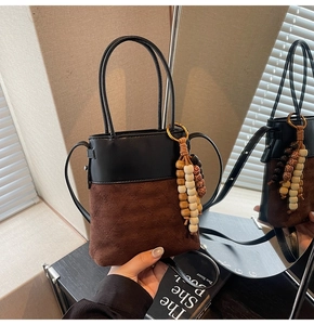Detail of vintage matte suede bucket bag with quilted patterns and wood bead tassels
