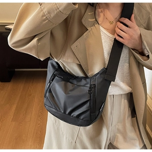 Detail of black nylon crossbody bag with multi-zipper pockets and wide woven strap