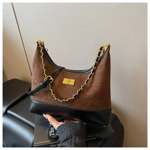 Detail of quilted suede shoulder bag with golden chain strap and twist lock closure