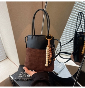 Detail of color-block bucket bag with suede quilting and decorative wooden beads