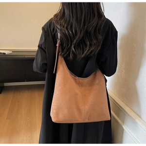 Detailed close-up of brown suede hobo tote bag texture on model in autumn attire