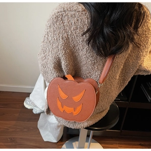 Detail of pumpkin-shaped crossbody bag with festive smiling face and orange PU leather texture