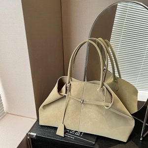 Detail of large tote bag in matte suede texture with long handles on a dark table