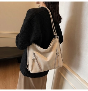 Detail of beige tote bag showing star charm zipper and textured dual strap design