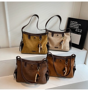 Detail view of large suede tote bags in four colors with beads and metal brand logo