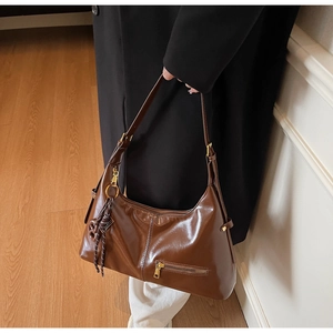 Sac hobo en cuir brillant marron avec détails dorés et nœud décoratif sur le côté