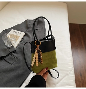 Detail of olive green suede bucket bag with quilted patterns and wooden bead tassel