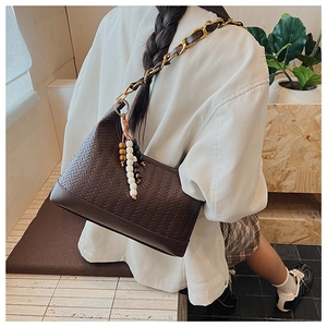 Detail of dark brown woven crescent bag with leather chain strap and colorful wood bead charm