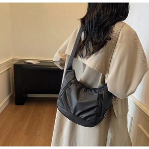 Detail of black oxford nylon crescent crossbody bag with zipper pockets and logo label