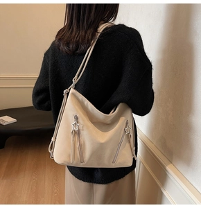 Close-up of a beige faux suede tote bag featuring star-shaped metal zipper pulls
