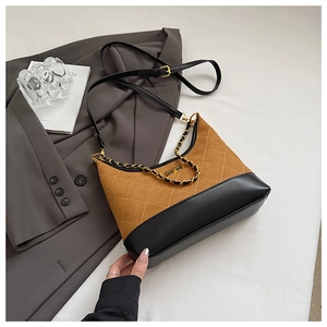 Detail of rhomboid quilted contrast bag with suede finish and gold metal chain